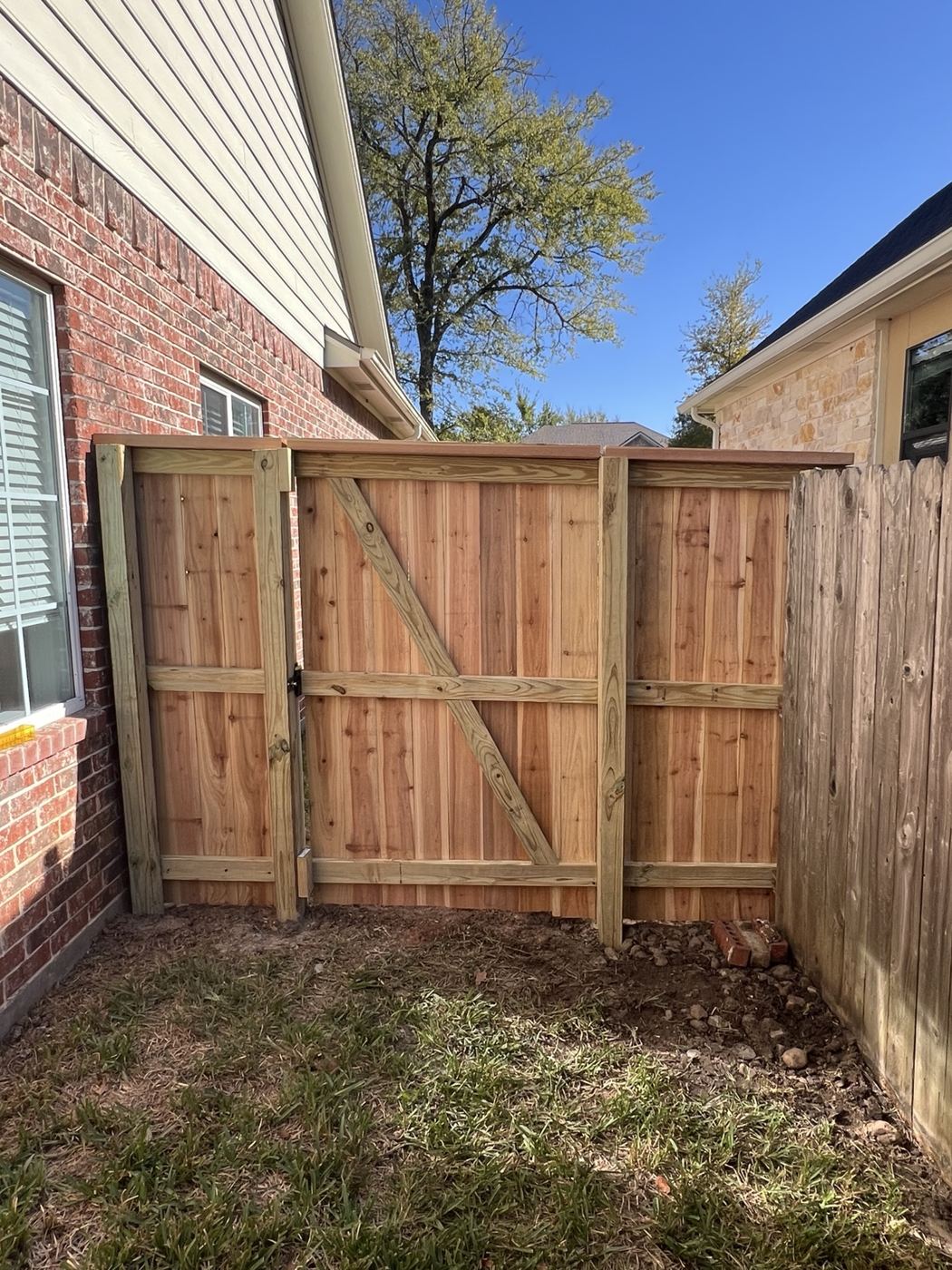 Custom cedar wood gate with cross bracing beside a brick home