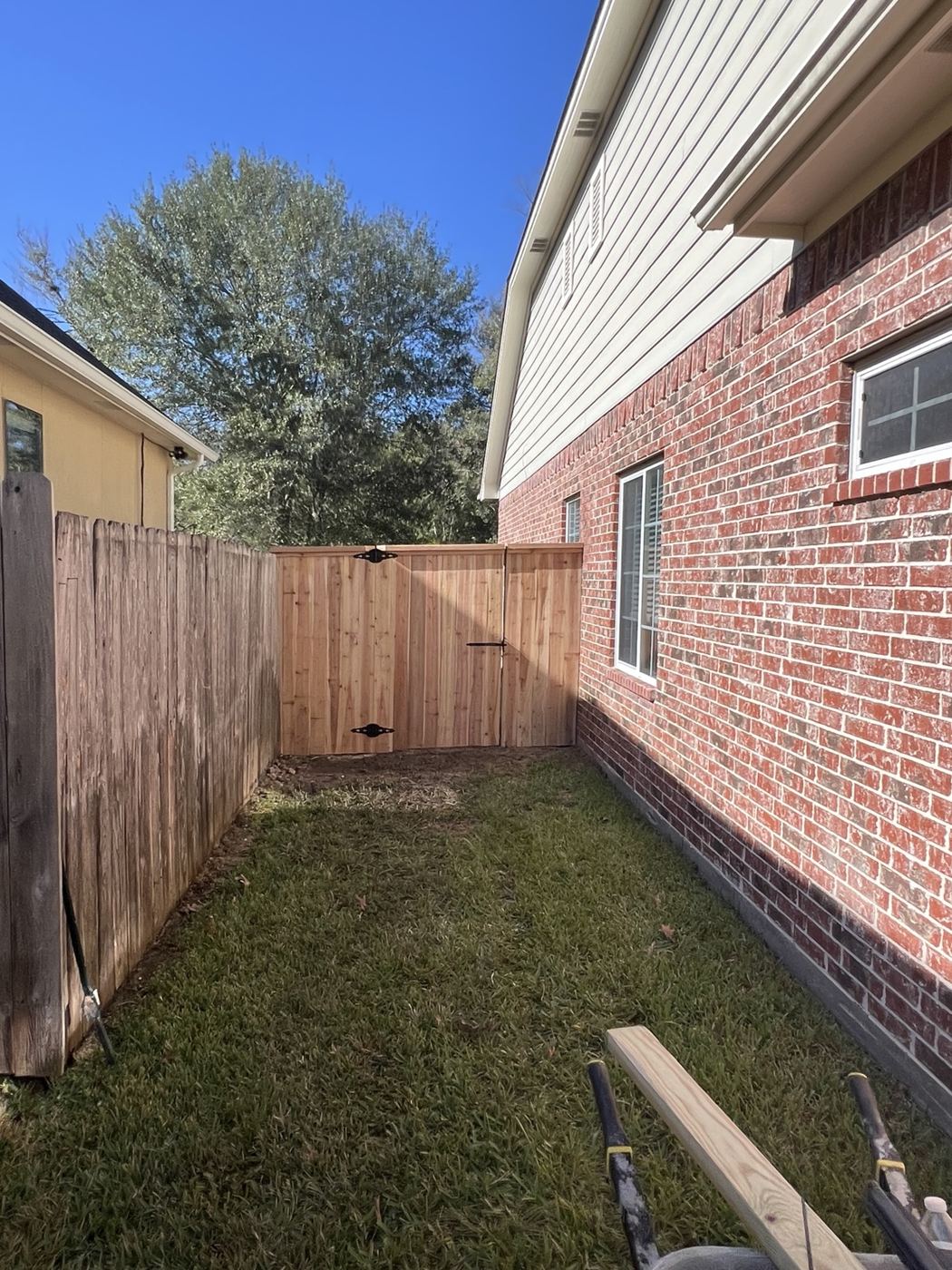Cedar privacy fence enclosing a narrow side yard next to a brick home