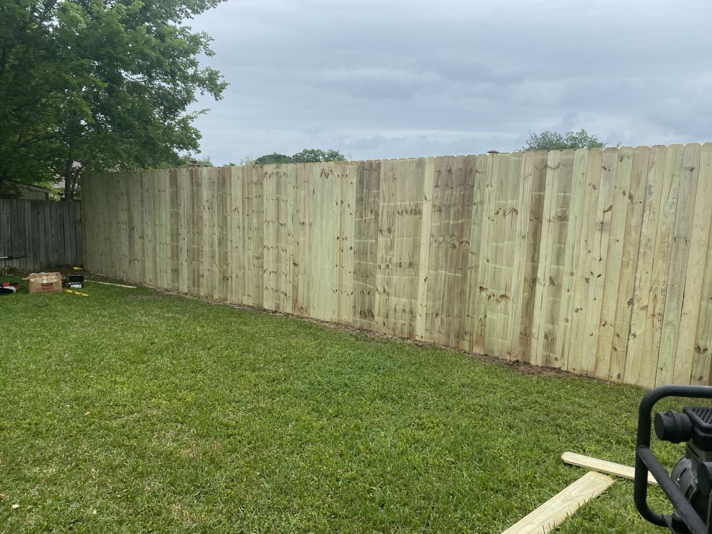 Tall wood privacy fence enclosing a backyard lawn