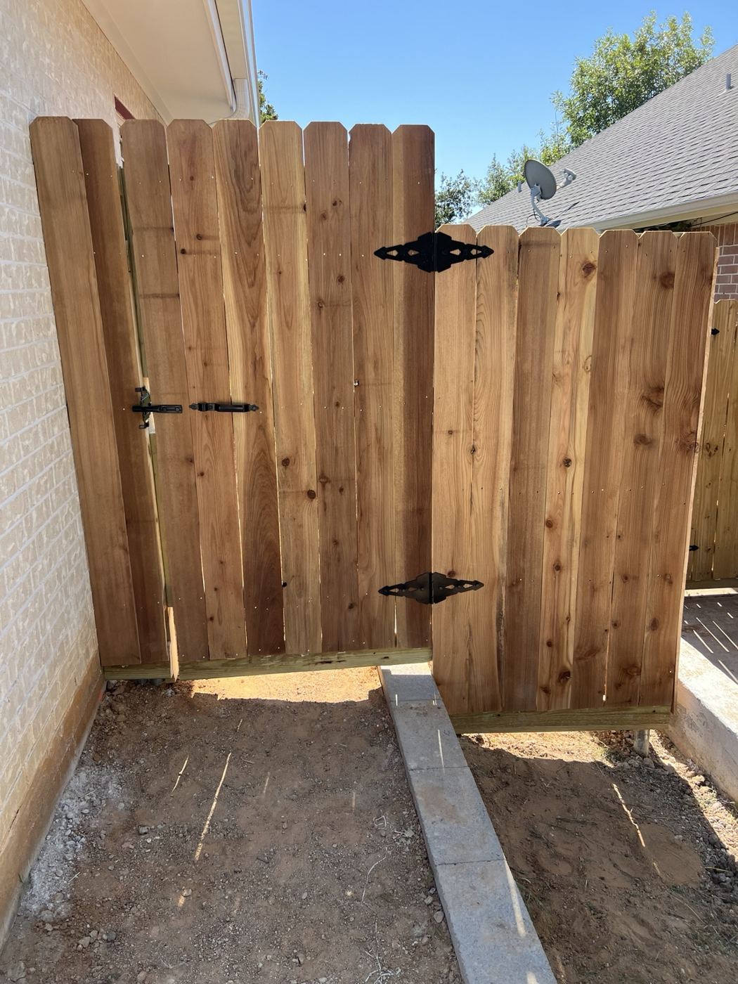 Newly installed cedar wood gate with black strap hinges