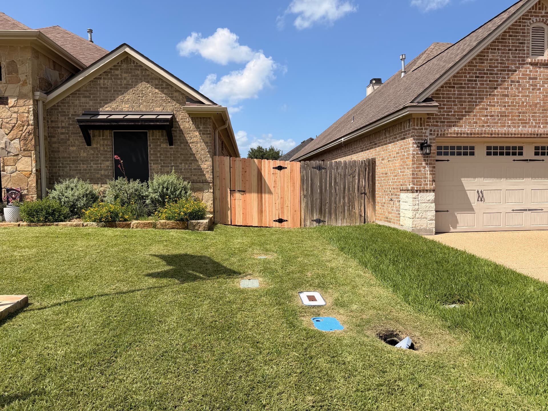 Fresh cedar gate installed next to weathered fencing beside a brick garage in Bryan, Texas