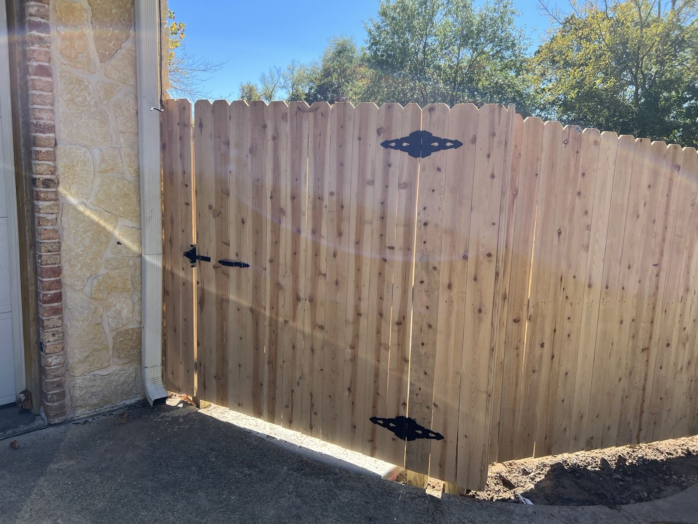 Cedar privacy fence panel meeting a stone home exterior