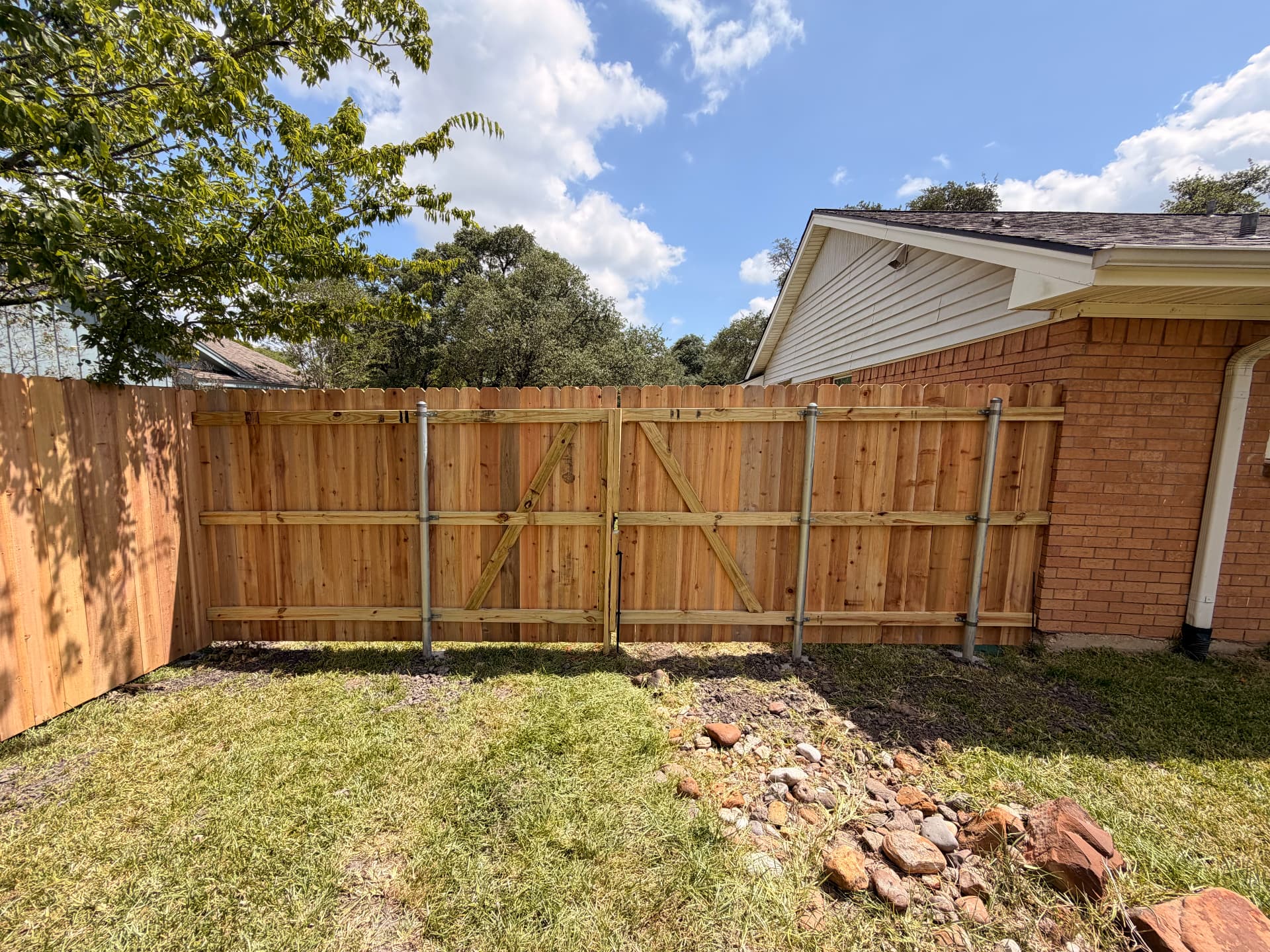 Back side of a cedar double drive gate showing galvanized steel posts and braced framing, Bryan TX
