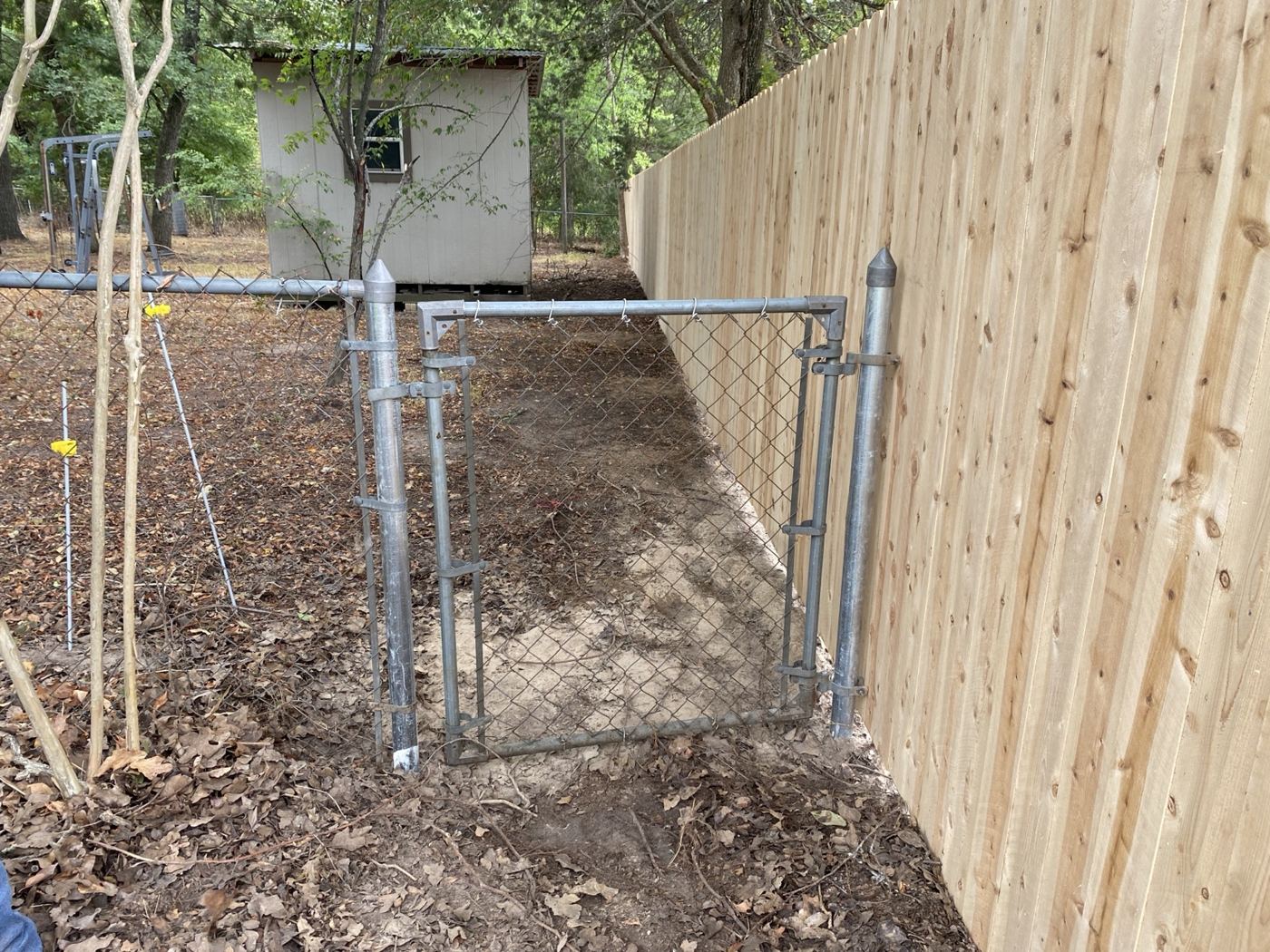 Chain link gate installed alongside a new wood privacy fence