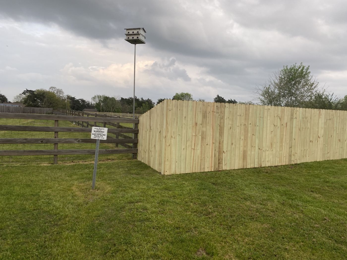 New wood privacy fence built next to an older ranch rail fence