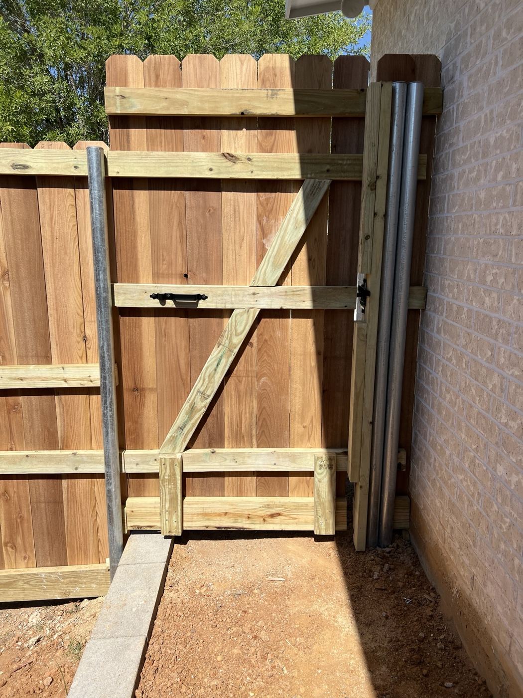 Back side of a cedar gate showing galvanized steel posts and wood framing